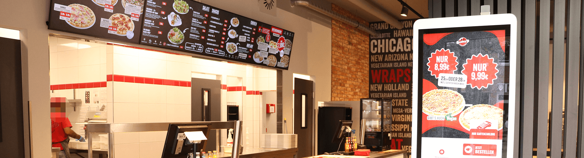 Innenbereich eines Smiley's Restaurants mit Verkaufstresen, Menütafeln und Bestellterminal