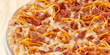 Pizza mit Käse, Spaghetti und gebratenen Speckstücken auf heller Tomatensauce.