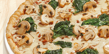 Pizza mit frischem Spinat und gebratenen Champignons auf heller Käsesauce