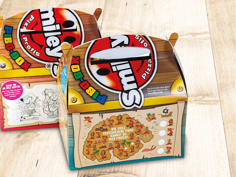Zwei Smileys-Pizzaboxen mit Piratenmotiv und Suchspiel-Aufdruck auf hellem Holzhintergrund.