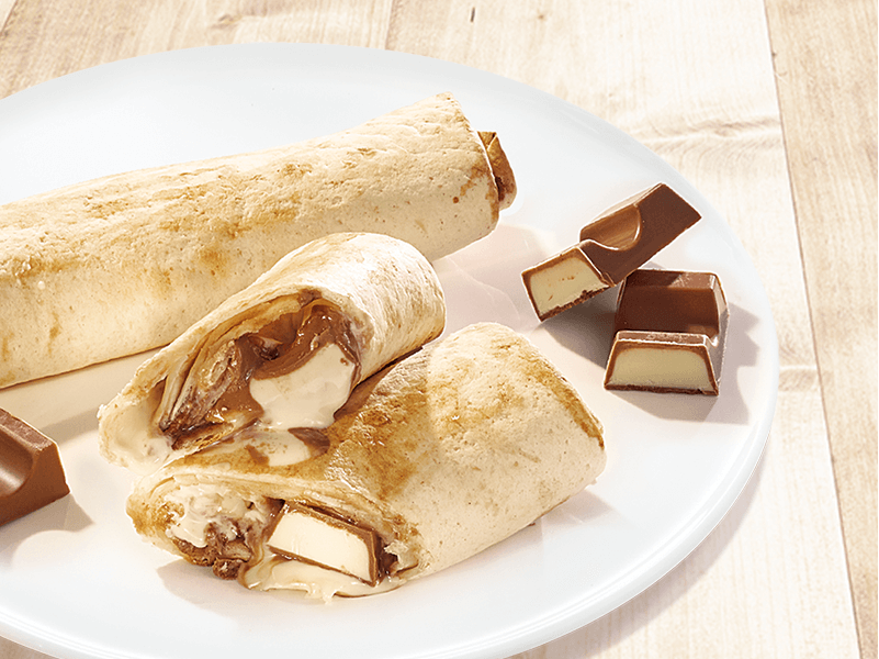 Gefüllte Wraps mit geschmolzener Schokolade und Creme auf weißem Teller, daneben Schokoladenstücke.
