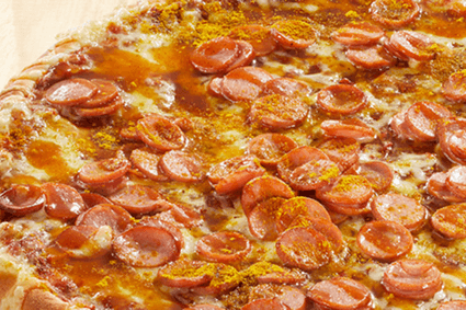 Pizza mit Würstchen, Curryketchup und Currypulver.