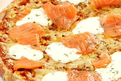 Pizza mit Räucherlachs, Crème fraîche und Dillspitzen.