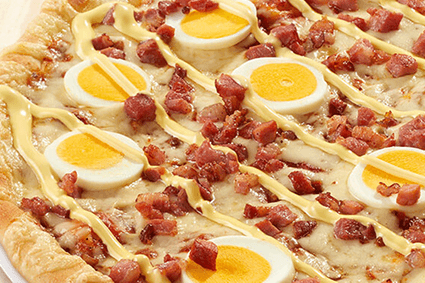 Pizza mit Baconwürfeln, Ei und Sauce Hollandaise.