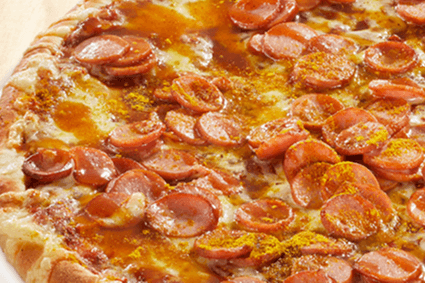 Pizza mit Würstchen, Curryketchup und Currypulver.