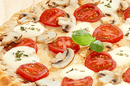 Pizza mit Mozzarella, Tomate, frischen Champignons und einer Prise Basilikum.
