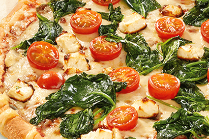 Pizza mit frischem Spinat, halbierten Cherrytomaten und kleinen Käsewürfeln