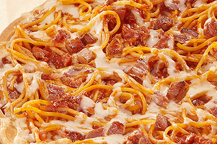 Pizza mit Käse, Spaghetti und gebratenen Speckstücken auf heller Tomatensauce.