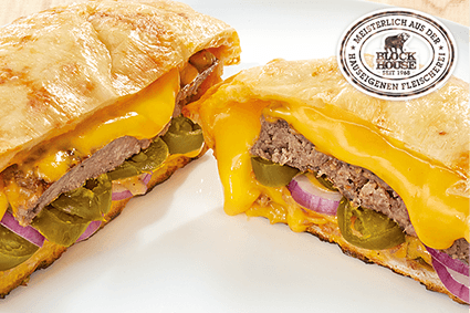 Burger im Smiley's Pizza-Teig, mit Cheddar-Cheese-Sauce, Jalapeños, roten Zwiebeln sowie Cheddar Schmelzkäse gefüllt und mit zartem Käse überbacken.