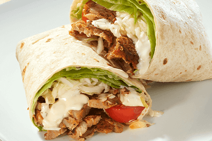 Wrap in zwei Hälften mit Hähnchen-Döner, Zwiebeln, Eisbergsalat, Tomaten, Krautsalat und Knoblauchsauce.